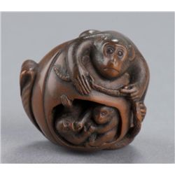 A wood netsuke of monkeys in peach.