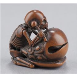 A wood netsuke of a skeleton on Mokugyo.