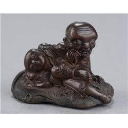 A wood netsuke of a sleeping man.