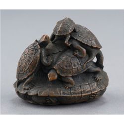 A wood netsuke of a turtle group.