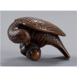 A wood netsuke of a eagle attacking a monkey.