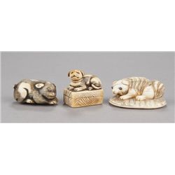 A group of three ivory netsuke of dogs.