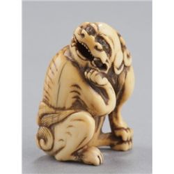 An ivory netsuke of a Shishi.