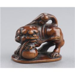 A wood netsuke of a Shishi.