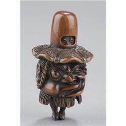 A wood netsuke of a boy in Bakemono costume.