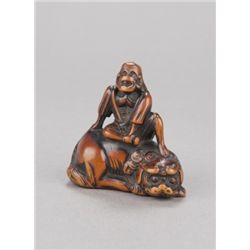 A wood netsuke of a Sennin on a shishi.
