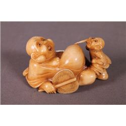 Ivory netsuke, man painting the Buddha's belly.