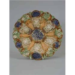A Castle Hedingham pottery wall plate moulded with masks and fruiting foliage