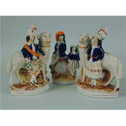 A pair of Staffordshire figures of children in Scottish costume standing beside sheep