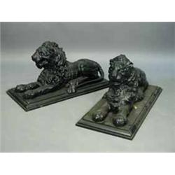 A pair of 20th Century composition figures of recumbent lions on iron plinths