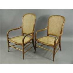 A pair of beechwood elbow chairs with caned backs and seats