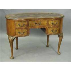 A walnut kidney shaped desk the top with a leather inset and burr walnut banding and carved borders 