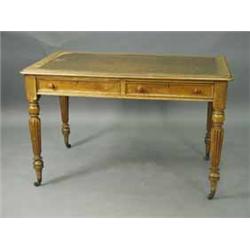 A Victorian oak two drawer writing table with turned reeded legs