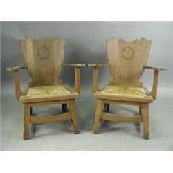 A pair of unusual late Victorian elbow chairs the shaped backs with carved motifs over drop in rush 