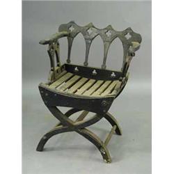 A Victorian 'Gothic' ebonised X frame elbow chair