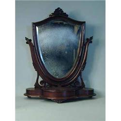 A Victorian mahogany toilet mirror with a shield shaped mirror on a serpentine base