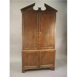 A George III oak cupboard with an architectural cornice over four panelled doors on bracket feet