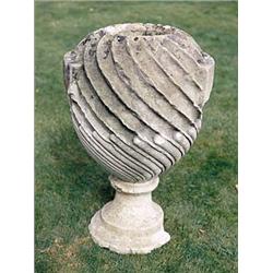 A late 18th century Bath stone vase of spirally fluted form, on a later composition stone circular r