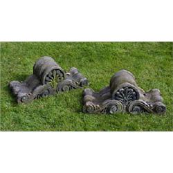 A pair of red sandstone gate pier finials, each carved with a stylised leaf motif above two "S" shap
