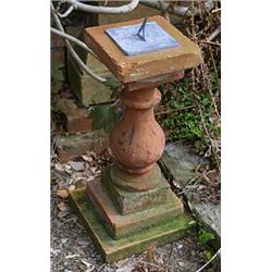 A terracotta balustrade, on square base, mounted with a lead sundial, the plate engraved with a sun.
