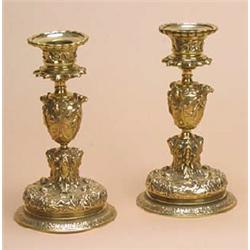 A pair of brass candlesticks, each with a scalloped nozzle, an urn shaped column cast with classical