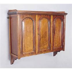 A late Victorian mahogany wall shelf, the three quarter gallery above three doors, with arched panel