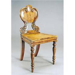 A William IV yew hall chair, the shield shaped back on foliate scroll supports with a solid seat, on