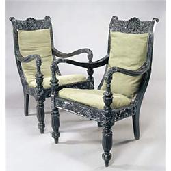 A pair of mid 19th century Anglo Indian ebony open armchairs, each carved overall with stylized flow