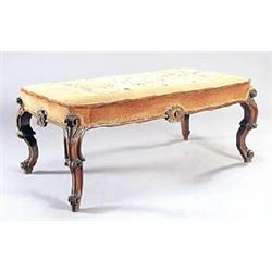 A Victorian mahogany rectangular stool, the seat upholstered with woolwork, with carved cartouches t