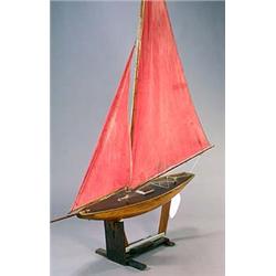 A large A-class pond yacht, circa 1920-30, of wooden plank-on-frame construction with plain varnish.