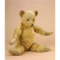 A 1920s teddy bear, the fully jointed golden plush body with worn velvet pads and glass eyes, the bo