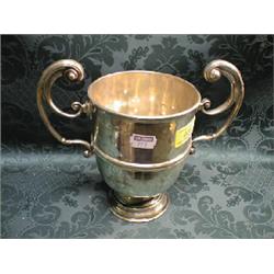 A Victorian silver trophy cup, with double flying scroll handles,  centrally reeded band and on s