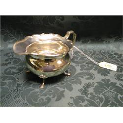 A George V silver cream jug, baluster, with everted and folded rim,  scroll handle, on shell and