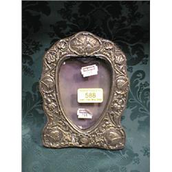 An Edward VII silver photograph frame, of shield shape, embossed with  putti, harebells and folia