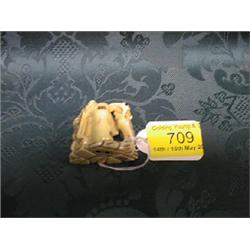 A Japanese ivory netsuke study of Shoki the Demon Queller seated at a  stove upon which rests a k