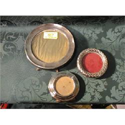 Three circular silver easel picture frames.