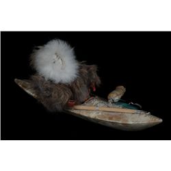 Inuit Kayak with Skin Covering a Sold Piece of Wood and Inuk in Traditional Attire. 12 1/2" L. 5" H.