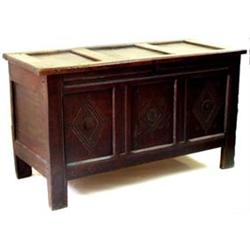 AN 18TH CENTURY OAK KIST: with triple panel top, the triple panel  front carved flowerheads withi...
