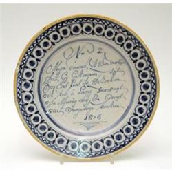 A Dutch delftware plate, no.2 from a series, painted with script and set pattern border in blue,...