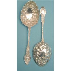 A pair of late Victorian silver dessert serving spoons with floral embossed bowls and scroll cast...