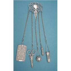 A late Victorian silver chatelaine fitted with notecase, scissors, tape measure, pencil and incom...