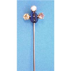 A gold stick pin claw set with an oval cabochon sapphire and 3 old brilliant cut tinted diamonds...