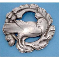 A Georg Jensen Sterling silver circular brooch designed as a dove within a foliate border, patter...