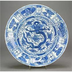 A Chinese Kraaksporselein charger centrally decorated with a dragon amongst clouds within a borde...