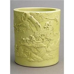 A pale yellow-glazed brushpot by Li Yucheng, carved with monkeys playing in a landscape, wood sta...