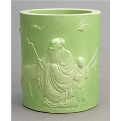 A pale-green glazed brushpot carved in high relief with a Shou Lao and a boy beside a deer and fi...