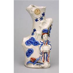 An Arita vase in the form of a lady holding a basket and standing by a naturalistically modelled...