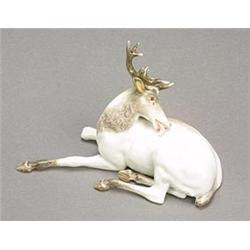 A Meissen model of a recumbent stag, head turned licking its back, sparsely coloured in shades of...