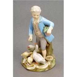 A Meissen figure of a goose-boy, modelled standing feeding a pair of geese and goslings, wearing...