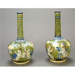 A pair of Italian maiolica Castelli-style bottle vases, painted with scenes of putti in an Italia...